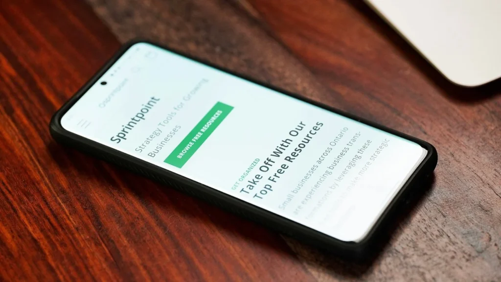 Celular sobre a mesa mostrando um site aberto